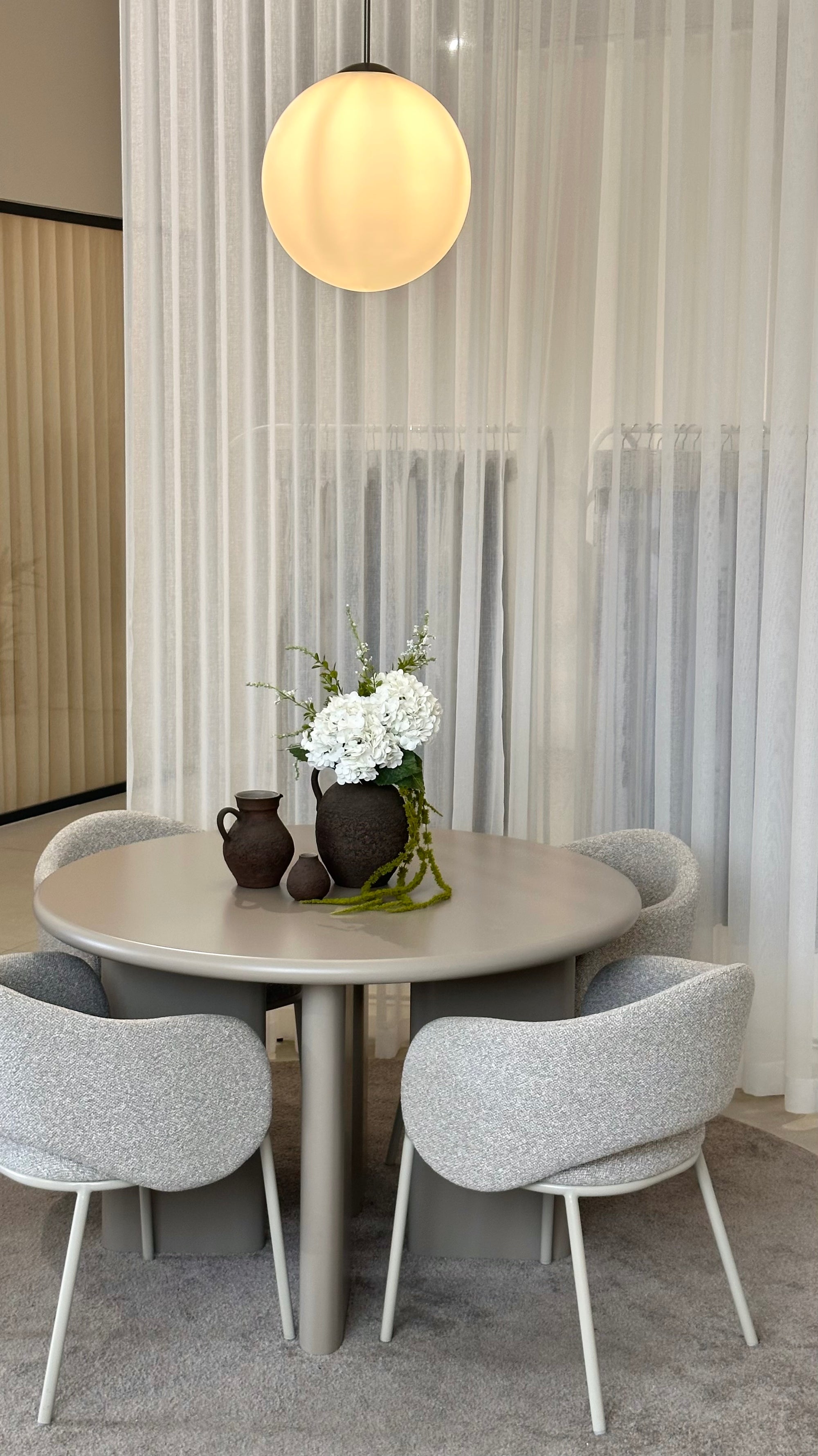 Grün-weißes Kunstblumen-Arrangement in Keramikvase auf hellem Beratungstisch
